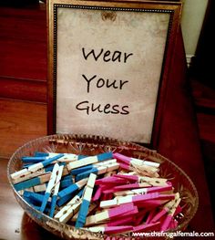 a bowl filled with clothes pins sitting on top of a wooden table next to a sign that says wear your guess