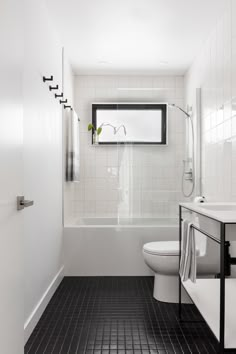 a bathroom with black and white tile flooring next to a bathtub, toilet and sink