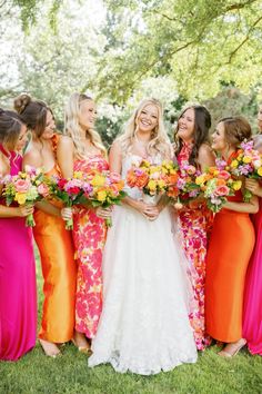 a group of women standing next to each other holding bouquets in their hands and smiling