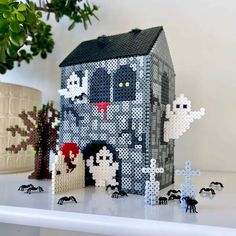 a house made out of perler beads and some other items on a white table