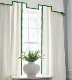 a vase filled with flowers sitting on top of a wooden table next to a window