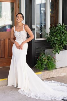 a woman standing in front of a building wearing a white dress and smiling at the camera