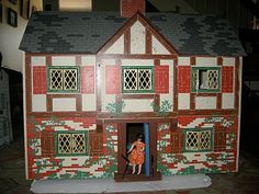 a doll house with two dolls standing in the front door and on the inside wall