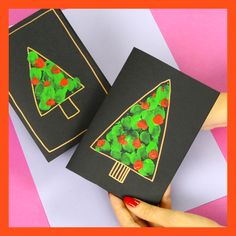 someone is holding up two cards that have christmas trees on them, one has green leaves and the other has red berries