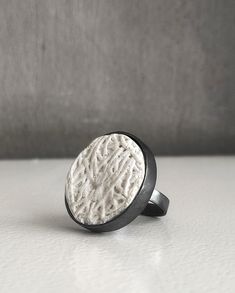 "This handcrafted round big concrete ring with Sterling Silver is the epitome of modern, geometric jewelry.Τhe ring is made of white concrete, has a special embossed surface and is bound with silver with an oxidation finish. It is an excellent choice for anyone seeking to make a statement while maintaining a modern and stylish look. Important Note: The oxidization will gradually wear off eventually, depending on use, the ring will get a sort of a vintage look. It can be easily re-oxidized. Αs each piece is individually handmade, slight variations in  texture are possible. In contact with skin, moisture and air, concrete becomes darker. DESCRIPTIONS and MEASUREMENTS: Materials:Oxidized silver and  white concrete . Diameter: 2,9 (cm) 1,14 (in)\" thickness 0,6 (cm) 0,24 (in\") ΑLSO COMBINED W Modern White Rings For Everyday Wear, Handmade White Rings For Everyday, Minimalist White Round Ring, Minimalist White Ring, Everyday Handmade White Rings, Modern Geometric Jewelry, Architectural Rings, Concrete Ring, Chunky Ring