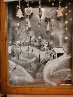 a glass frame with christmas decorations hanging from it's sides and snowing on the ground