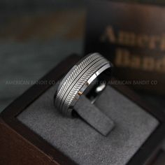 a men's wedding band with silver inlays sits on top of a wooden box