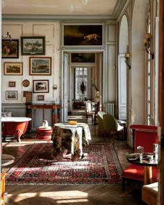 a living room filled with furniture and pictures on the wall behind a table in front of a doorway