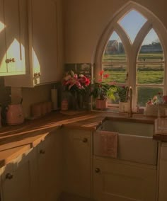 a kitchen with an arched window and flowers on the counter top in front of it