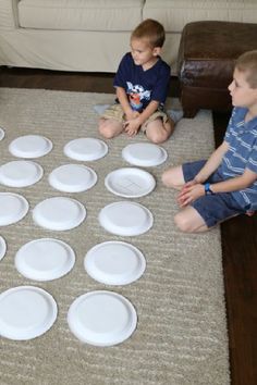 two boys sitting on the floor playing with paper plates