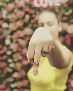 a woman pointing at the camera with her finger in front of a flowery background