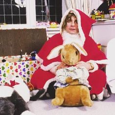 a man dressed as santa claus holding a stuffed animal in his lap with other cats around him