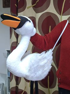 a person holding a stuffed bird in front of a curtain