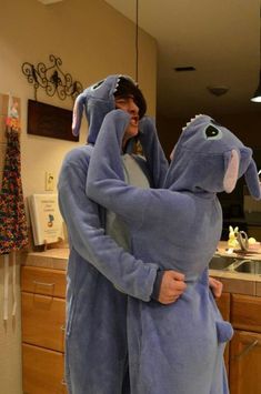 two people in blue ones are hugging each other while standing in the middle of a kitchen