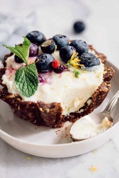 a piece of cake on a plate with blueberries and other fruit toppings next to a fork