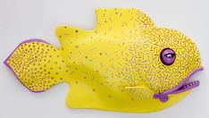 a yellow and purple fish shaped object on a white surface