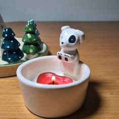 a small candle in a bowl with a bear figurine next to it on a table