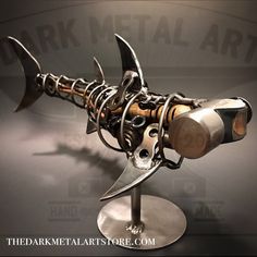 a metal sculpture of a fish on a stand with two knives sticking out of it's mouth