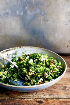 a bowl filled with broccoli and other food on top of a wooden table