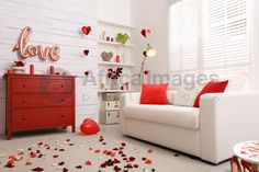 a living room with white walls and red pillows on the floor, along with rose petals scattered all over the floor