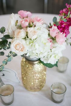 a vase filled with white and pink flowers next to two votive cups on a table