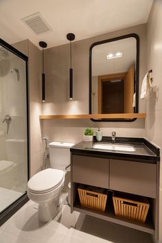 a bathroom with a toilet, sink and shower stall in the corner is lit by two lights