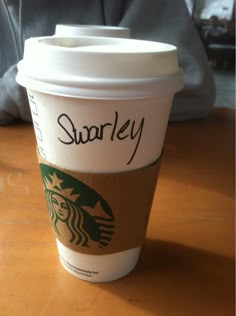 a starbucks cup sitting on top of a wooden table