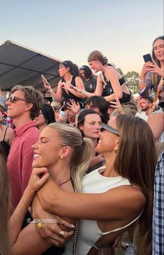 a group of people standing around each other in front of a crowd with cell phones