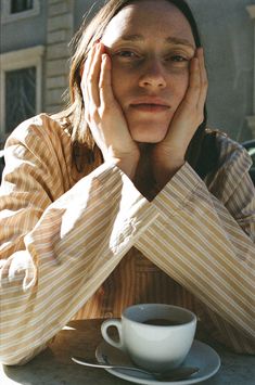 a woman sitting at a table with her hands on her face and holding her head