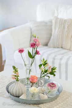 a tray with vases and flowers sitting on a table in front of a couch