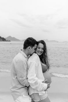 a pregnant couple embracing on the beach