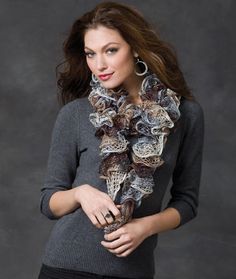 a woman is wearing a scarf with flowers on it and posing for the camera in front of a gray background