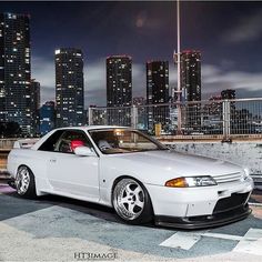 a white car parked in front of a city skyline