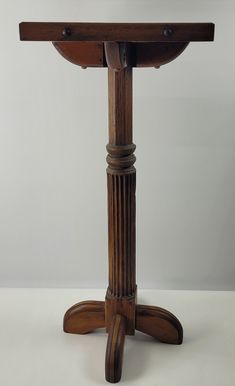 an old wooden table with two legs and a round top, on a white surface