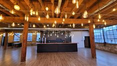 an empty room with lots of lights hanging from the ceiling and wooden beams on the ceiling