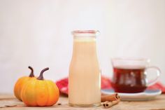 a glass bottle filled with liquid next to an orange pumpkin and cinnamon on a table