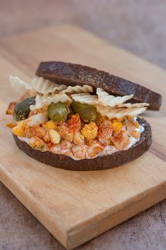 a sandwich with various toppings on a wooden cutting board