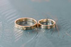 two gold wedding rings sitting on top of a table