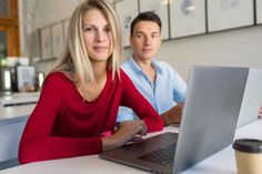 a man and woman sitting at a table with a laptop computer in front of them