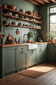 a kitchen filled with lots of green cupboards and wooden shelves next to a window