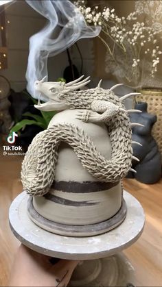 a cake with a dragon on top is being held up by someone's hand