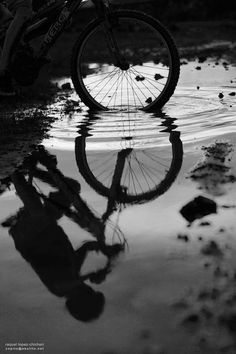 a person riding a bike on top of a body of water next to a puddle