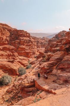 a person walking on a path in the middle of some rocks and dirt with mountains in the background