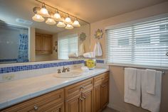 a bathroom with wooden cabinets and white towels on the rack, along with a large mirror