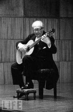 a man sitting in a chair playing an acoustic guitar