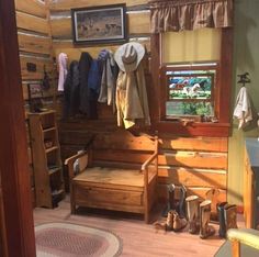 the inside of a cabin with wooden walls and wood flooring, clothes hanging on hooks