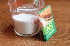 a glass measuring cup filled with milk next to a packet of sugar