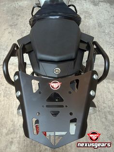 the front end of a black motorcycle parked on top of a cement floor next to a wall