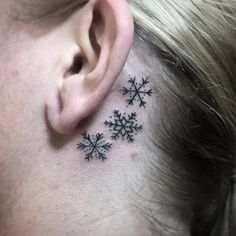 a woman's behind the ear tattoo with snowflakes on her left side