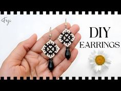 a pair of black and white beaded earrings in the palm of someone's hand